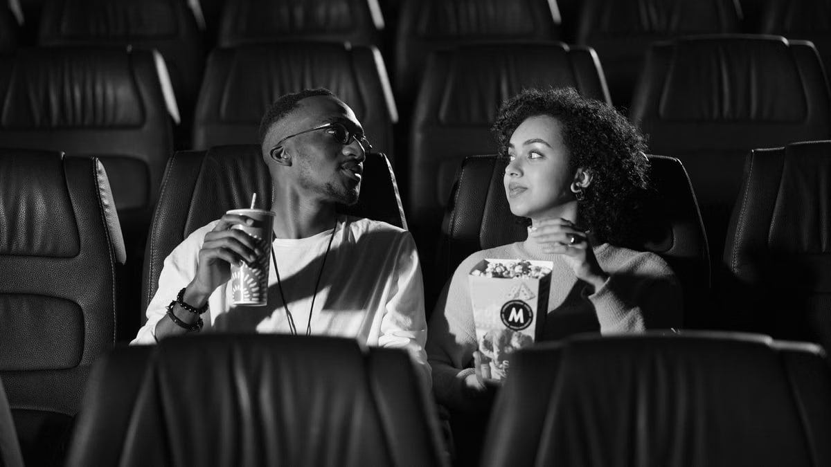 A couple enjoying snacks while watching a movie in an empty theater.